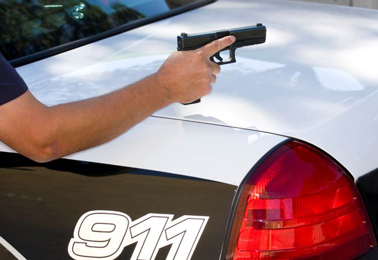A hand holds a gun above a car labeled "911". It is likely a police car used for illustrative purposes on a content management system.